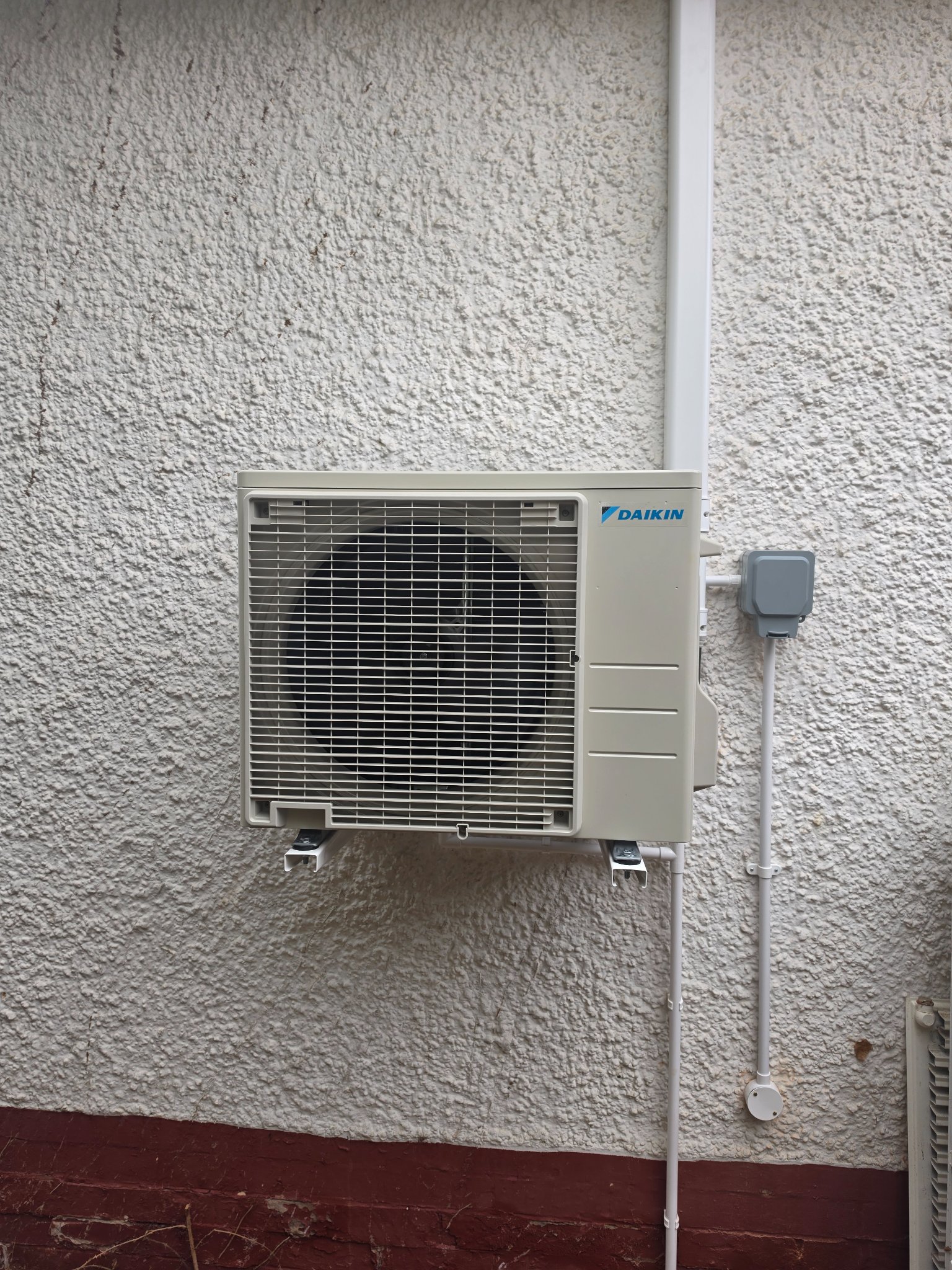 Daikin air conditioning outdoor unit mounted on external wall brackets at a bungalow in North Petherton