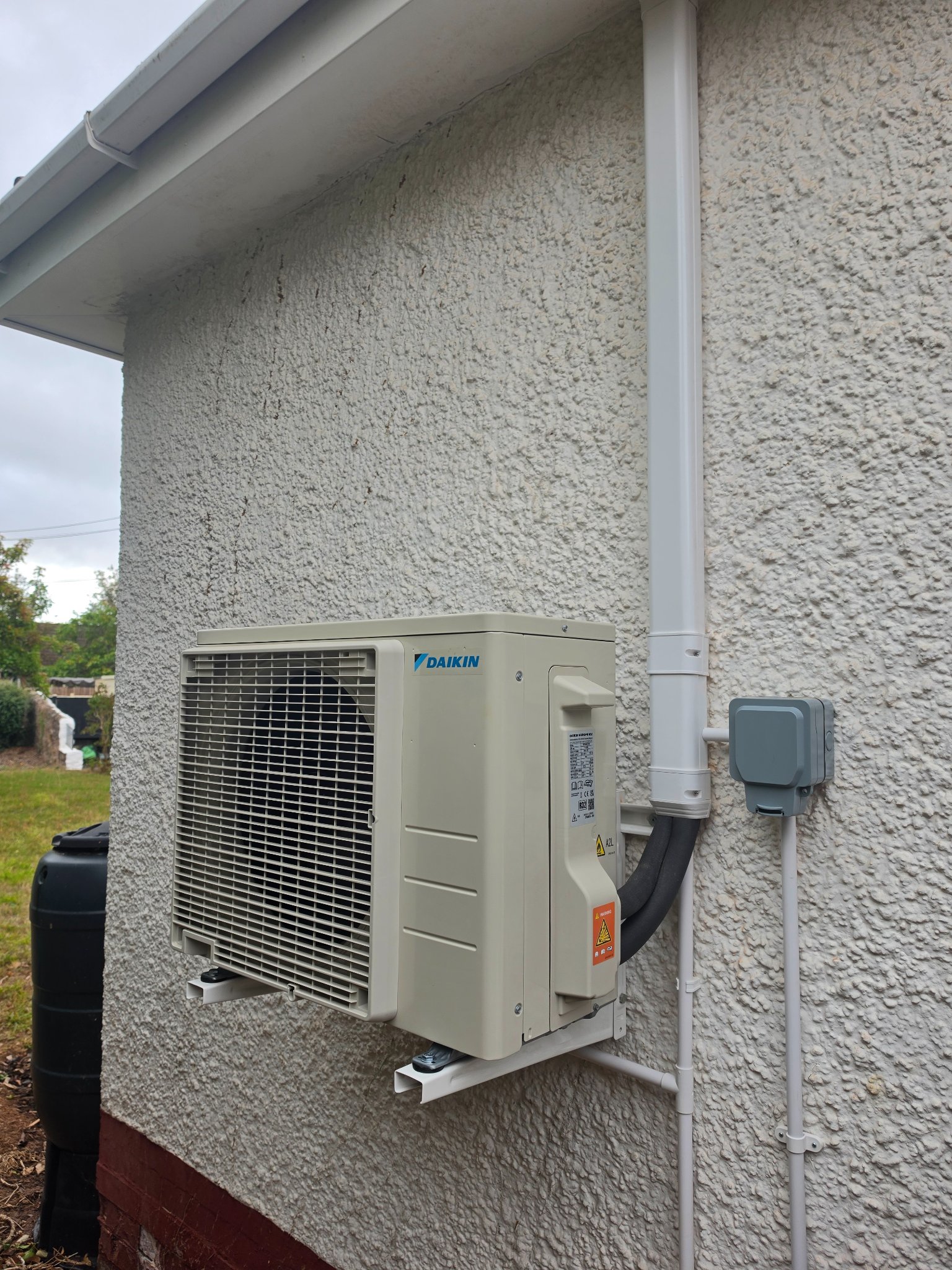 Outdoor air conditioning unit and insulated pipework on the side wall of a bungalow in North Petherton