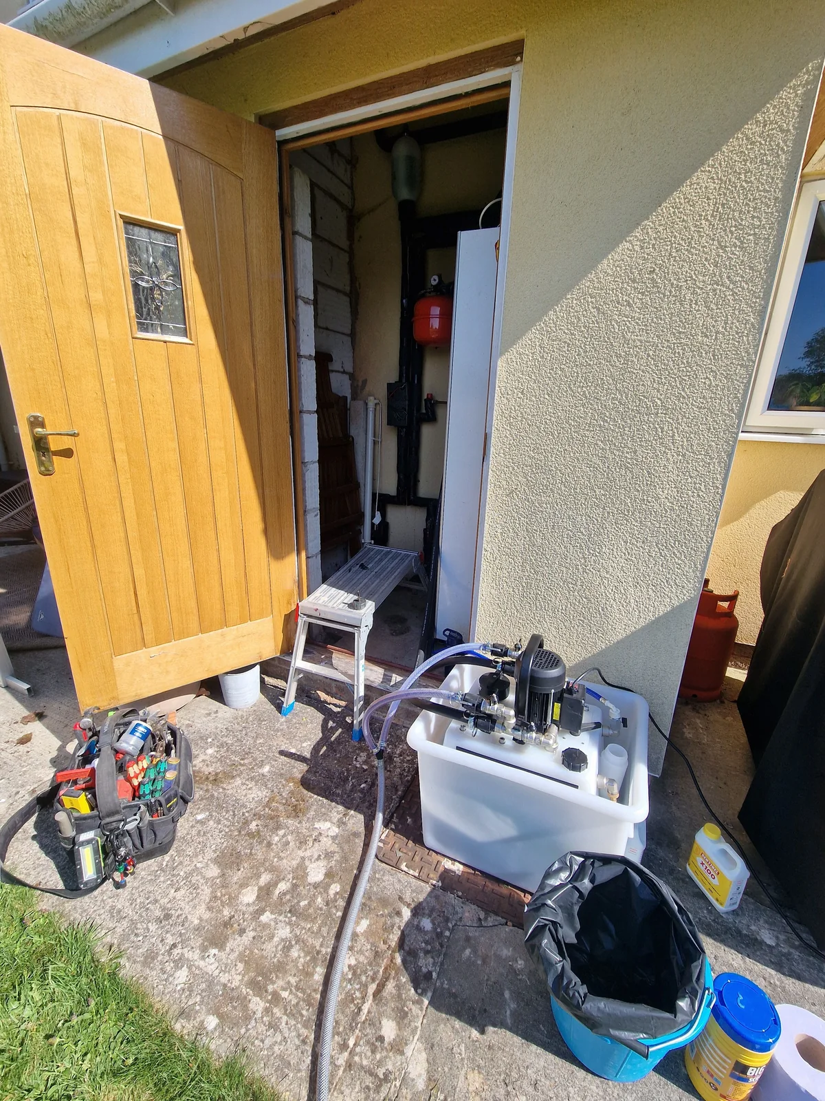 Power-flushing rig set up outside the customer's property with hoses running in through the door